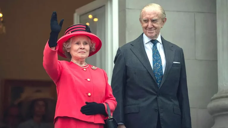 La regina Elisabetta II (Imelda Staunton) e il principe Filippo (Jonathan Pryce) salutano una folla invisibile dal balcone di Buckingham Palace nella stagione 6 di The Crown, parte 2