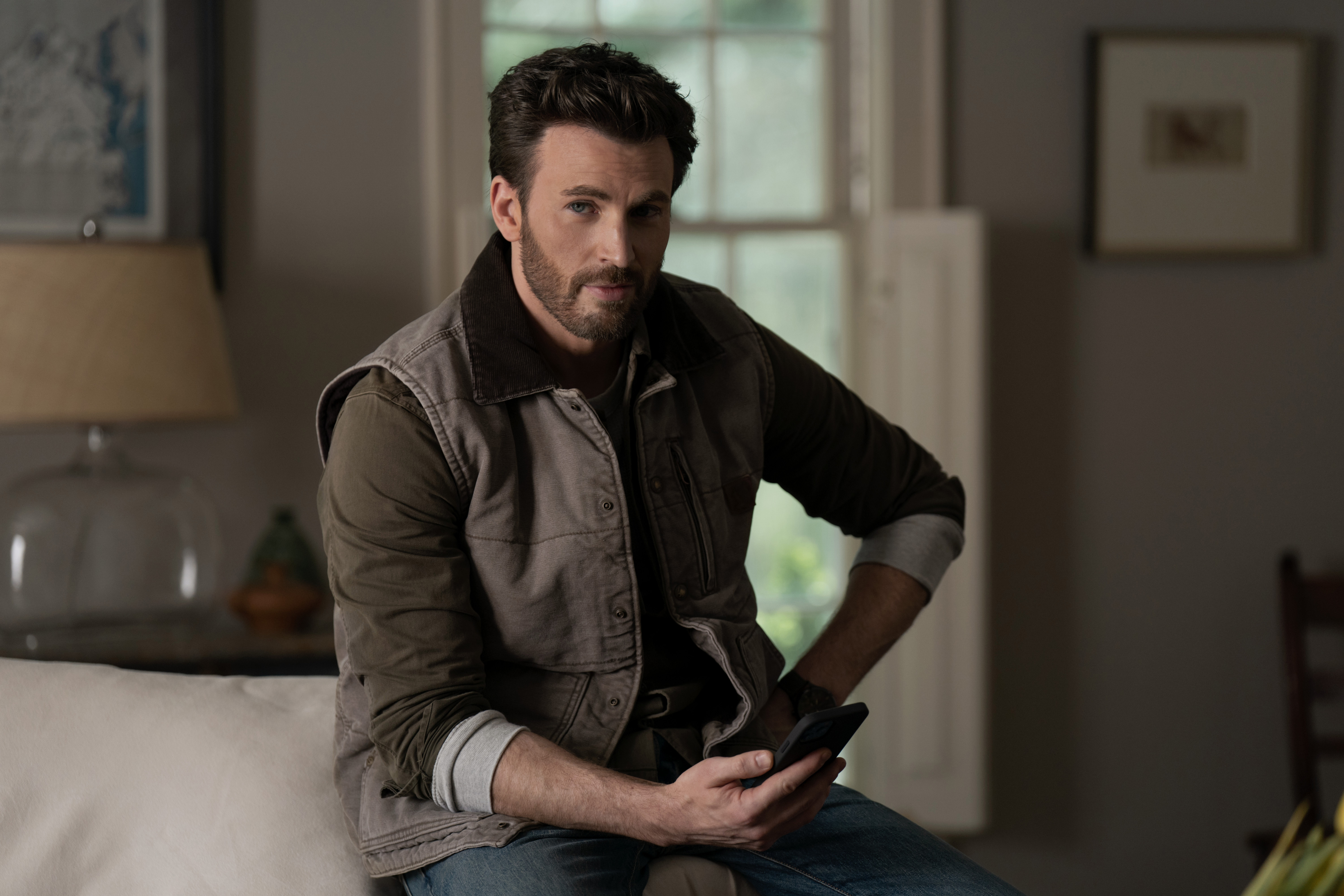 Chris Evans è seduto su un divano in Ghosted.